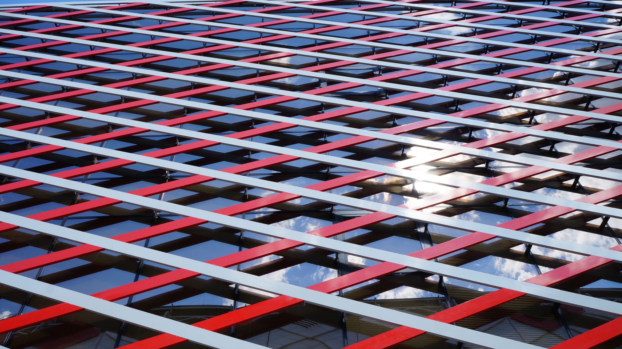 Modern building facade with red and blue geometric pattern and sky reflection
