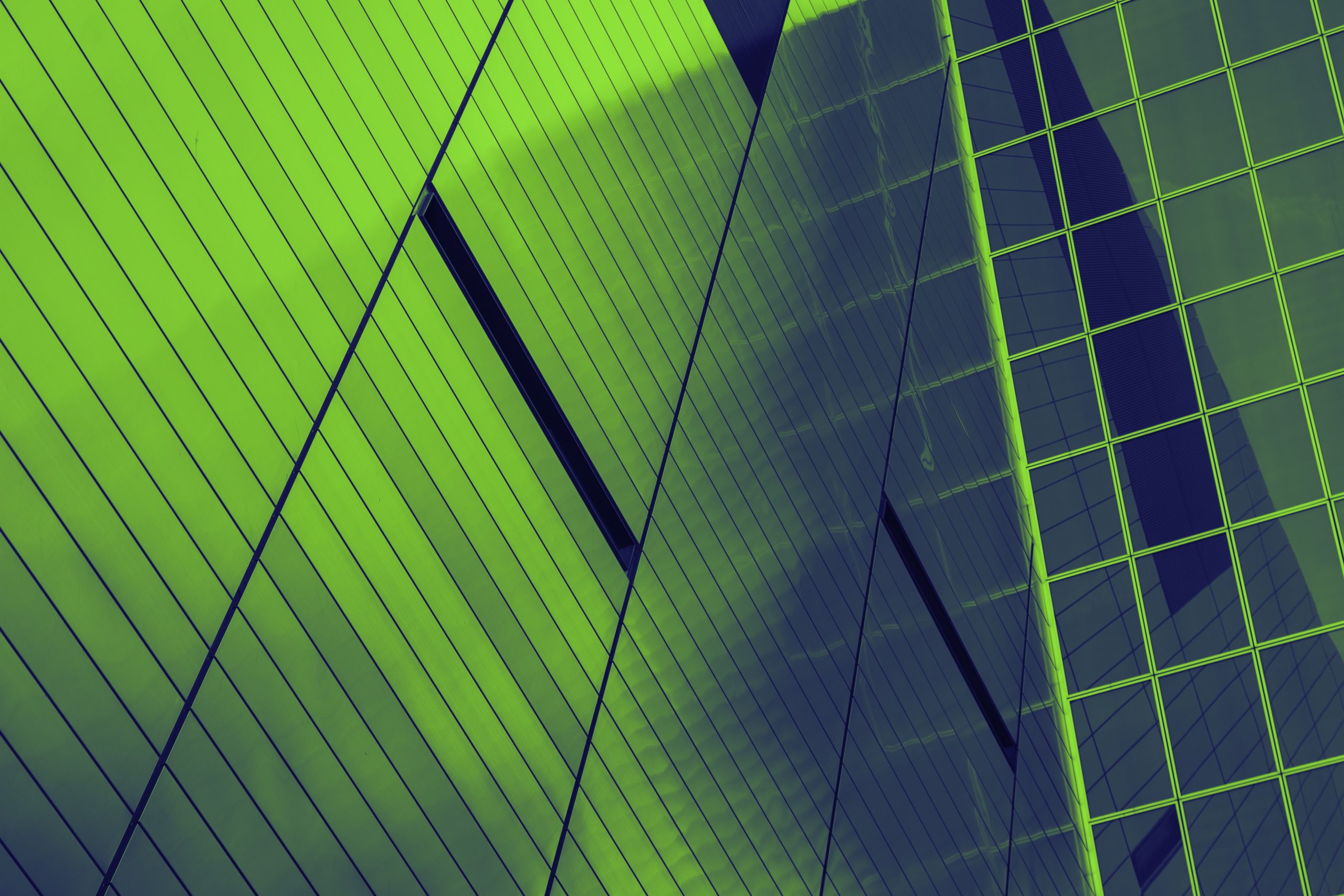 Abstract close‑up of modern glass and metal building façades in green and blue tones.