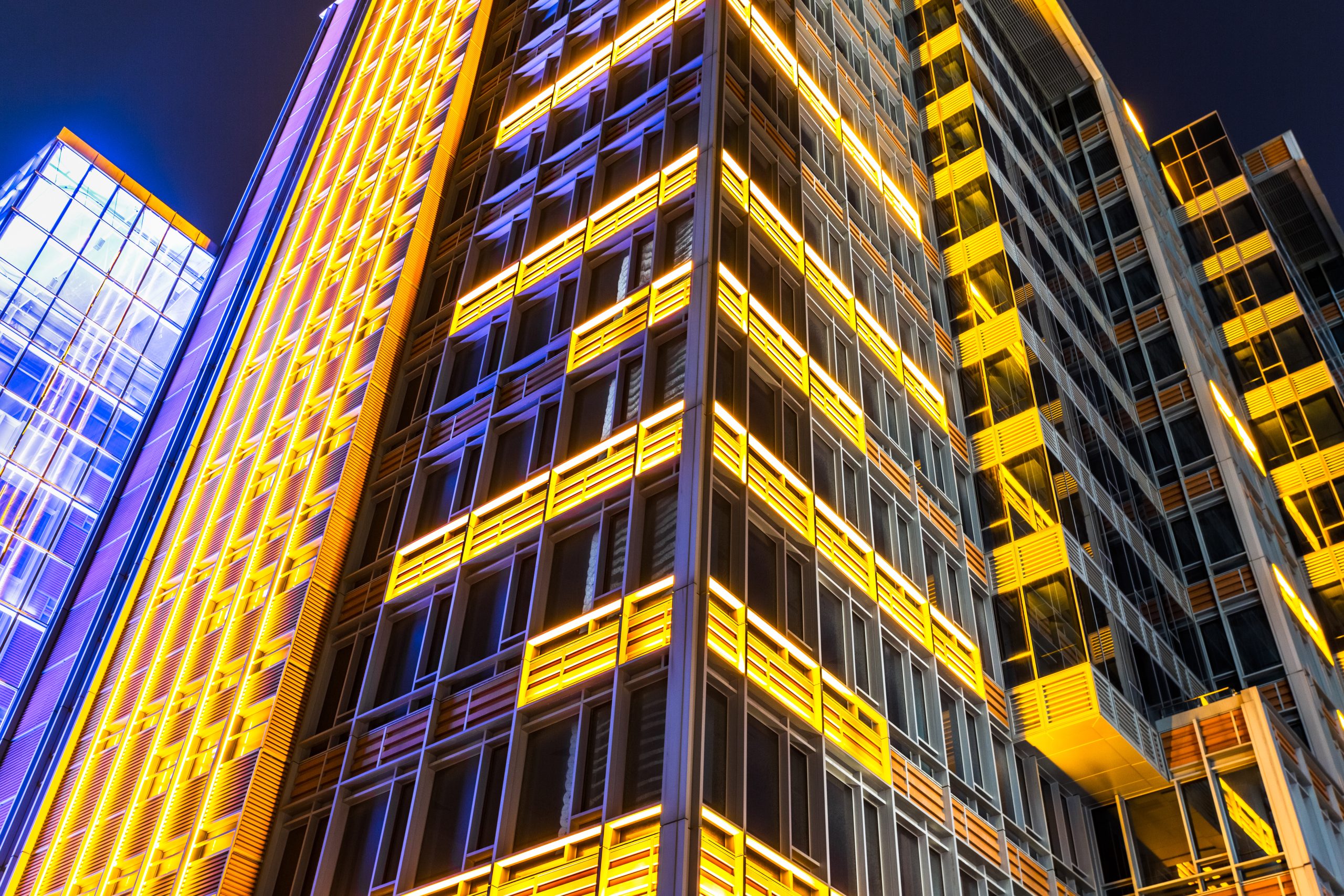 Modern office building with bright yellow and blue illuminated panels at night for Capital Quarter February 2026