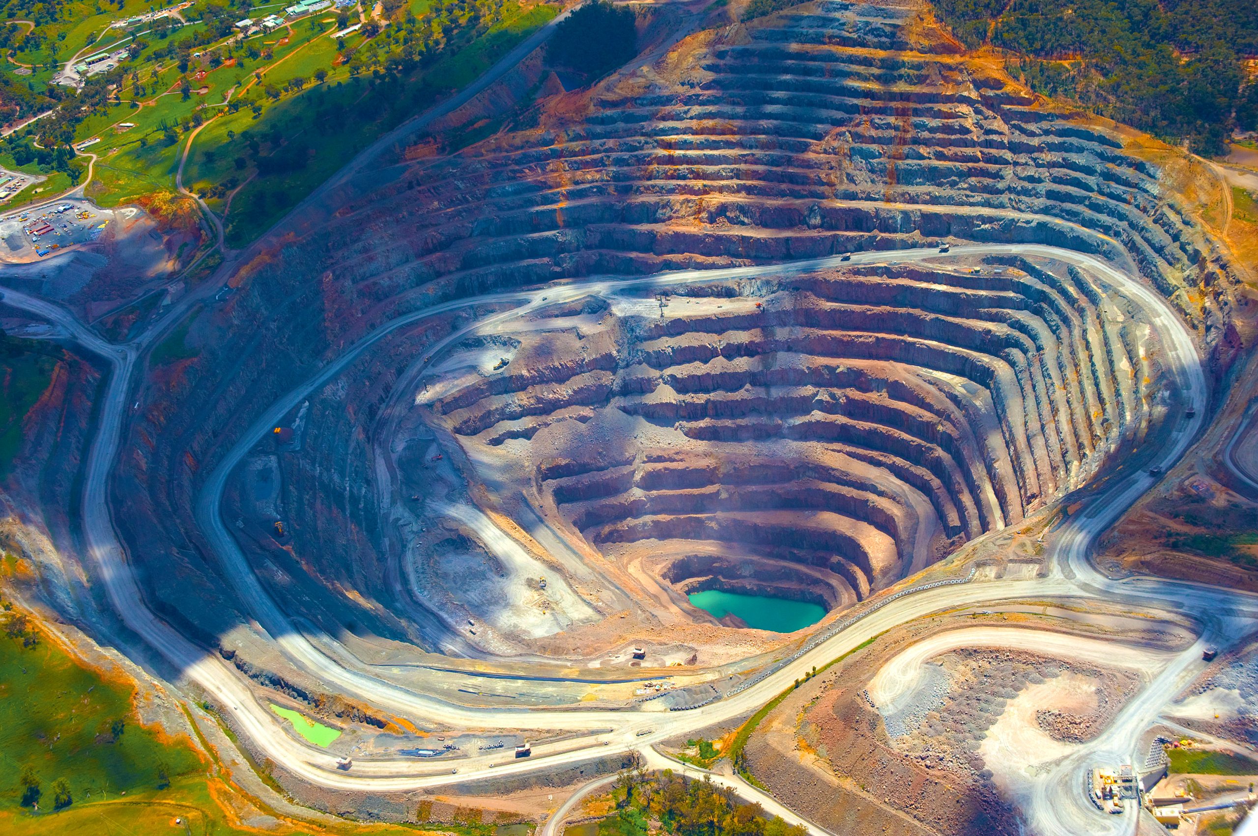 Aerial view of a large open‑pit mining site with terraced benches, haul roads and exposed rock formations.