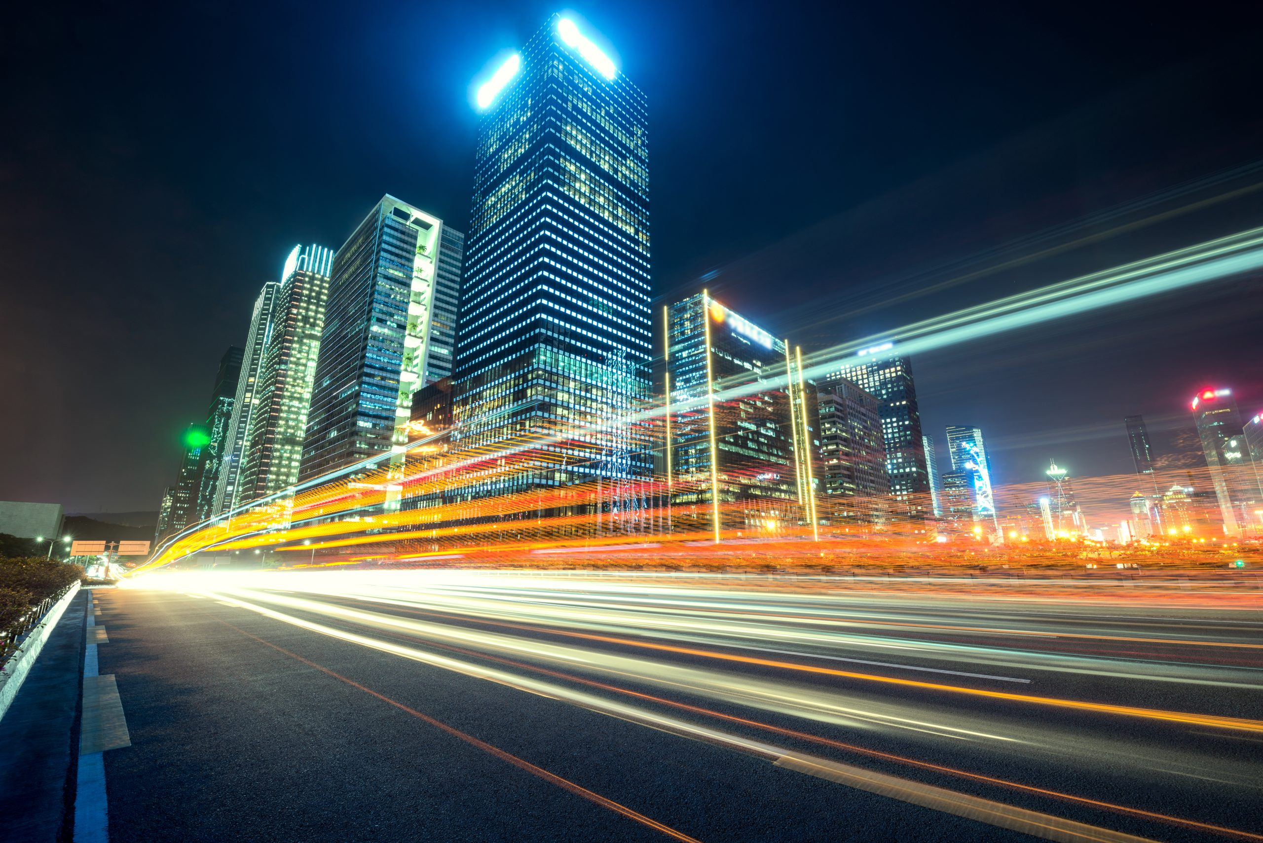 Night‑time city skyline with illuminated office towers and light trails
