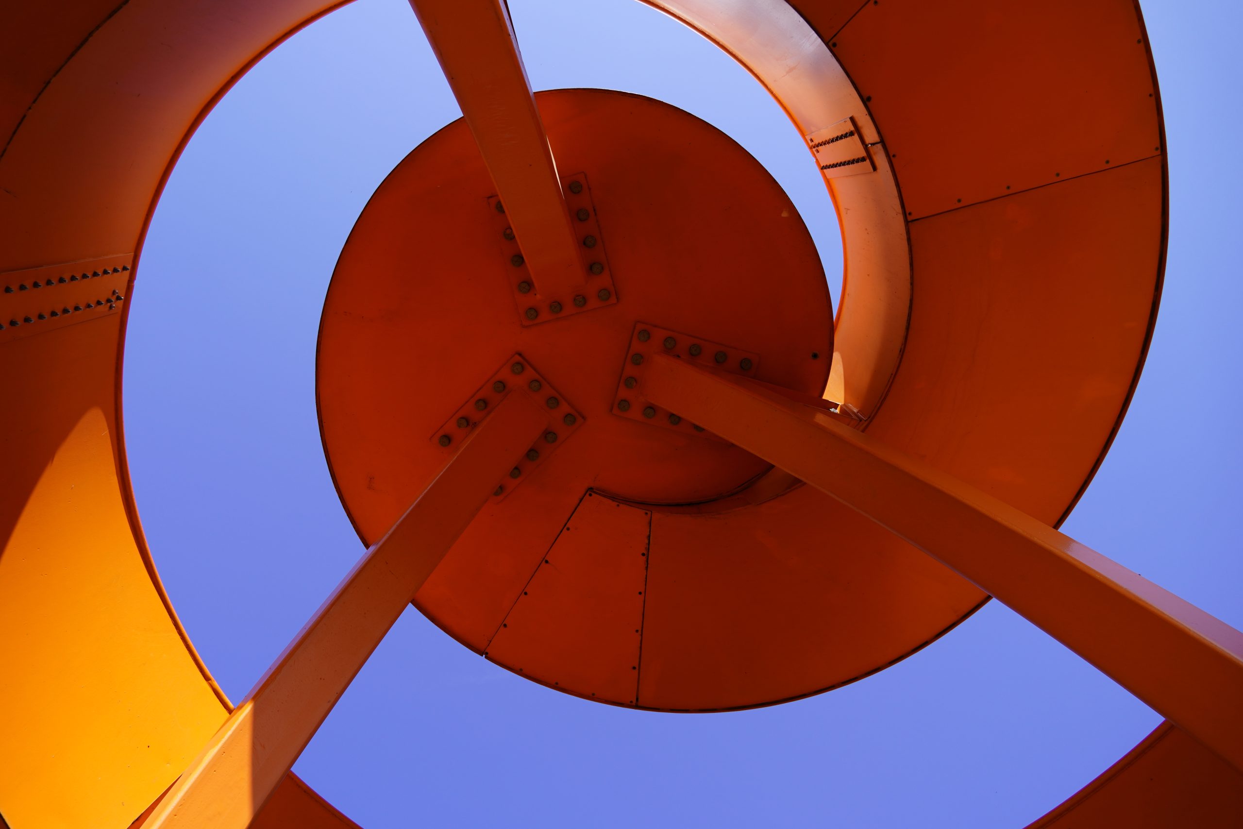 Detail of a spiral viewing platform. Abstract architecture in bright orange and blue sky background.