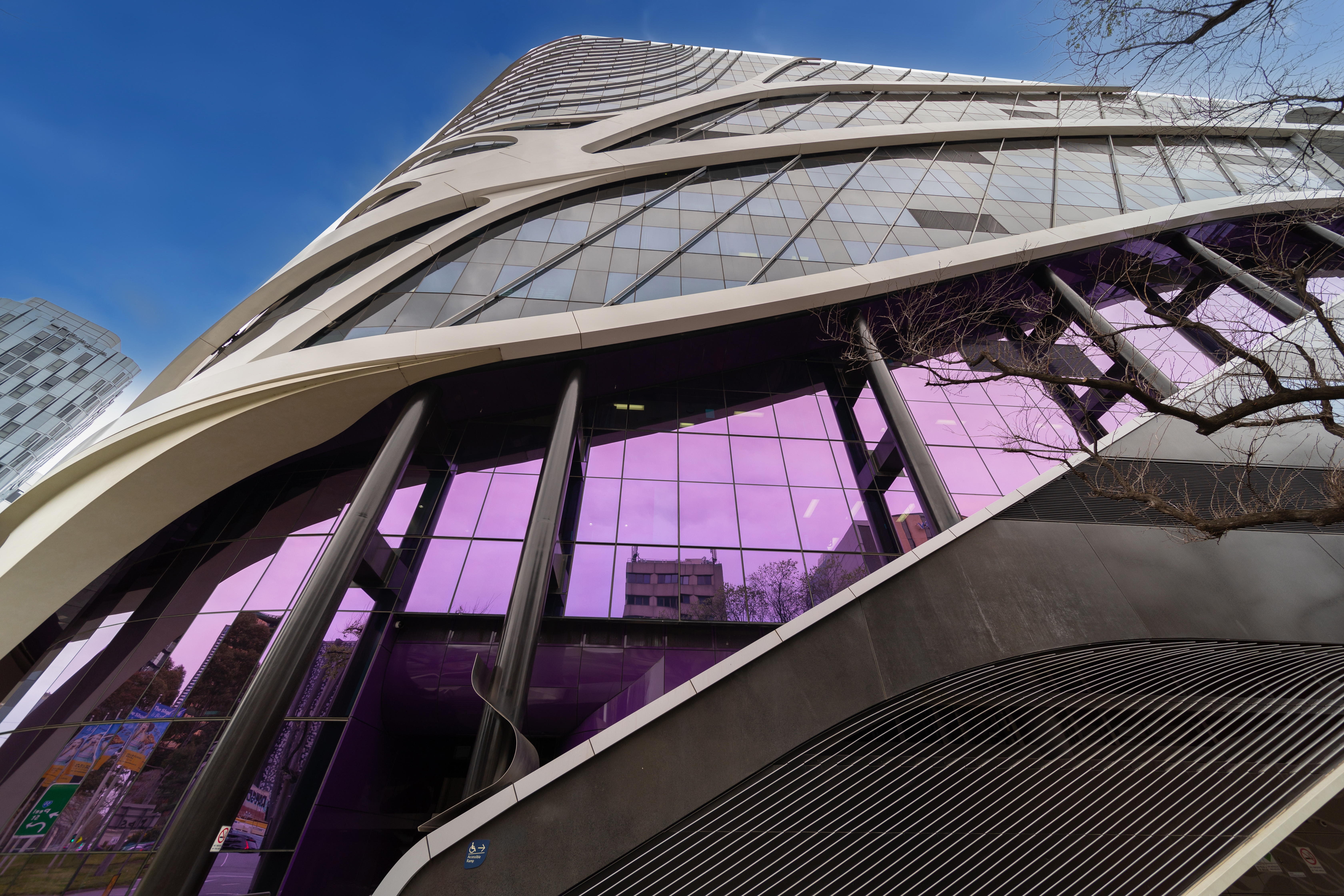 Modern glass office building with curved architectural design viewed from street level.