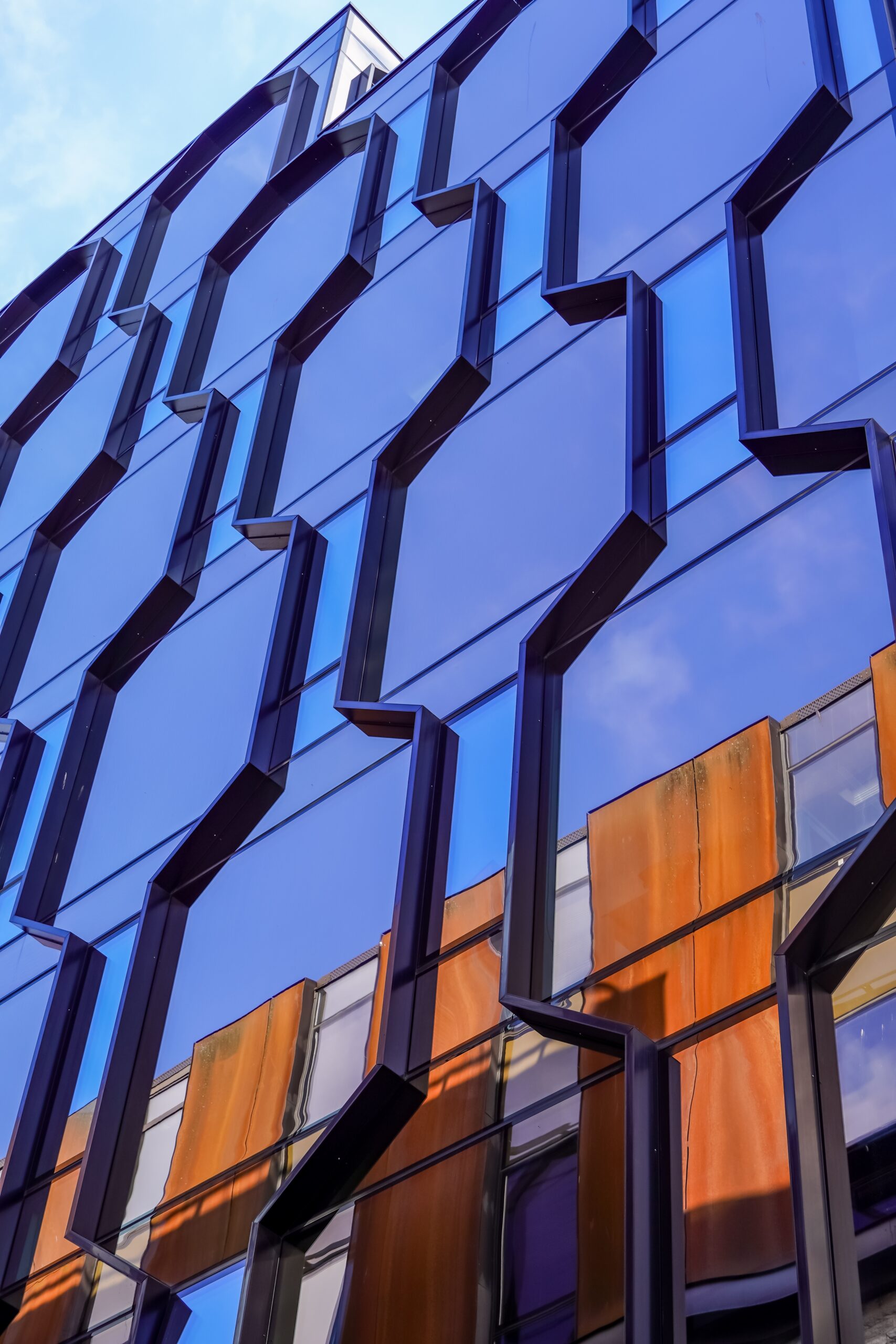 Modern glass office building facade with reflective blue panels and geometric architectural design